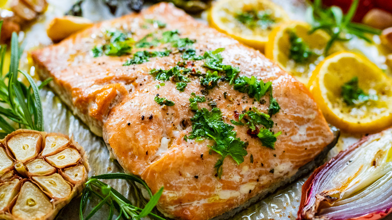 Salmon dressed with herbs & surrounded by lemons and garlic