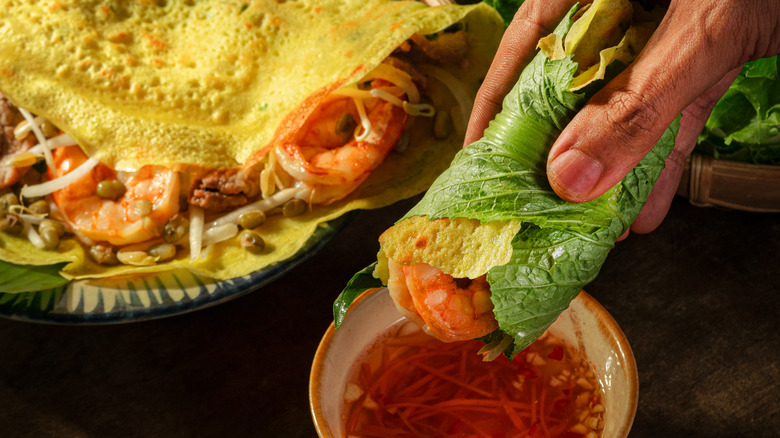 Banh xeo being dipped into nuoc cham