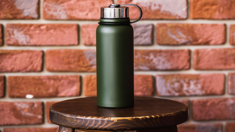 A green coffee thermos on a stool