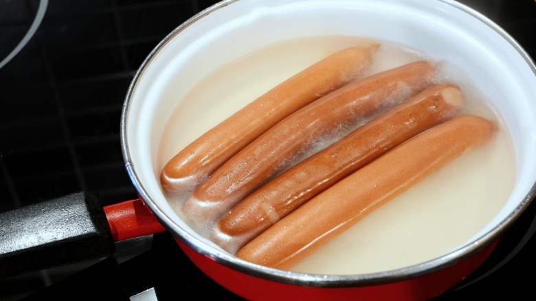 Four hot dogs sitting in water.