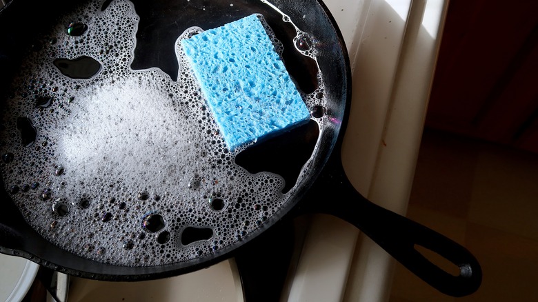 Handwashing a cast iron skillet with a sponge