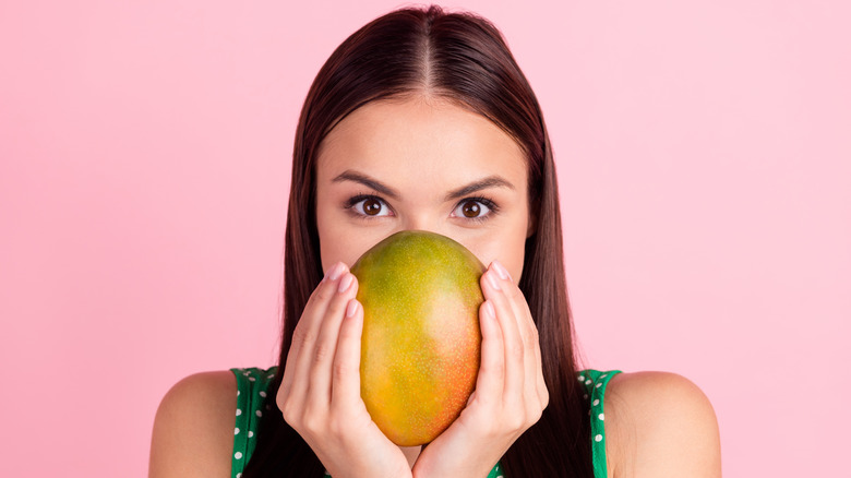 Brunette woman holding ripe mango