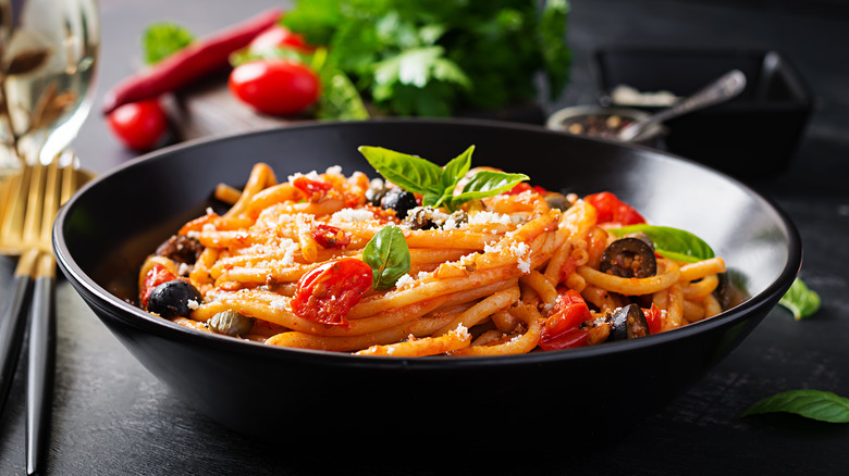 puttanesca pasta in a black bowl