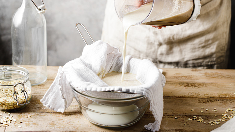 Pouring oat milk through sieve