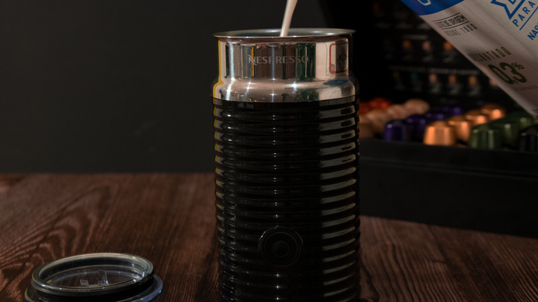 A person pours milk into a Nespresso Aeroccino