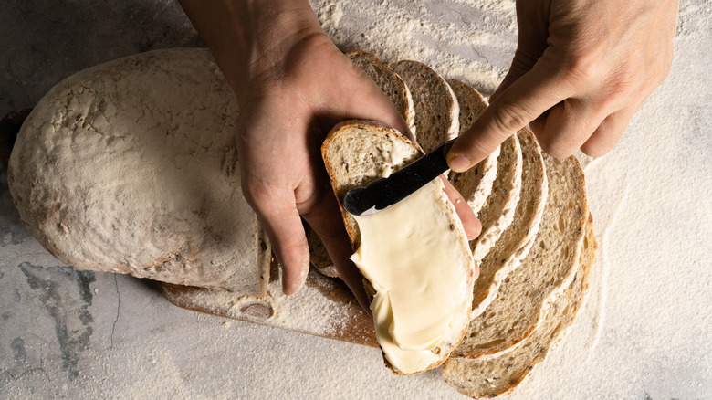 Hands spreading butter on bread