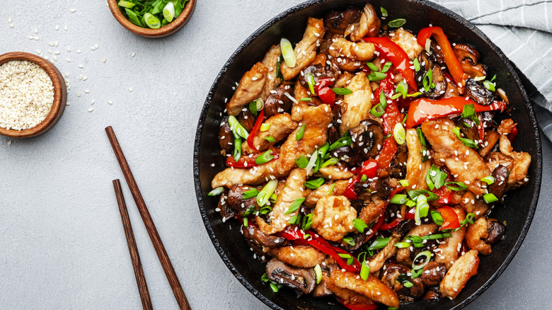 Bowl of stir fry with sesame seeds and chopsticks