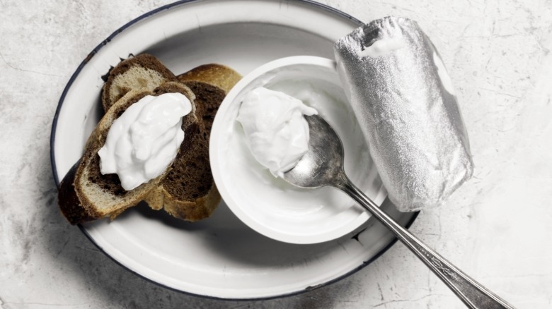 open container of yogurt with a spoon in it next to pieces of toast