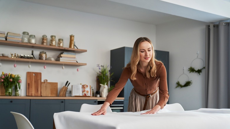 woman placing tablecloth on table