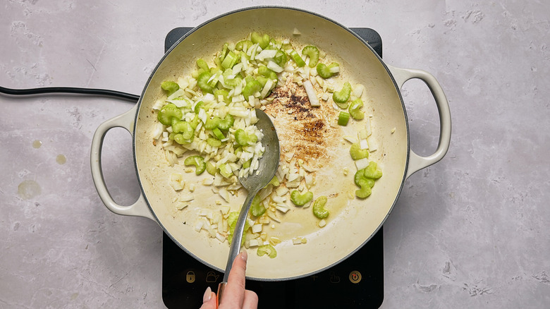 hands stirring vegetables in skillet