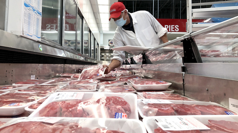 A butcher at Costco adjusting the refrigerated meats