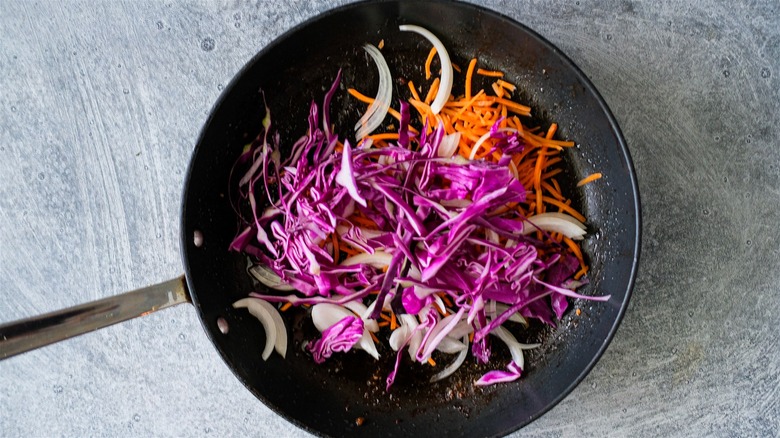 stir frying cabbage, carrots, onions