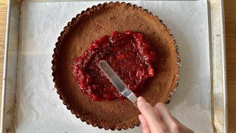 spreading cranberry jam on tart crust
