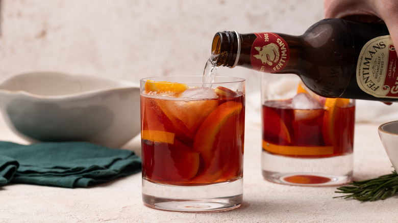 pouring ginger beer into cocktail