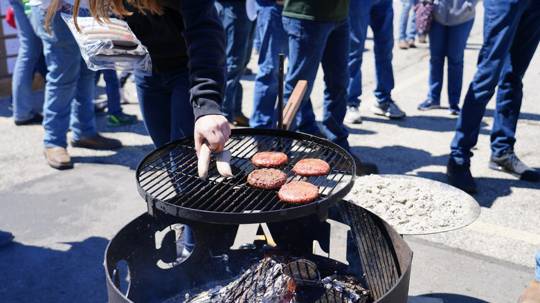 Burgers and brats cook on a grill 