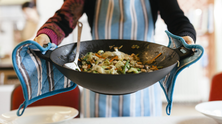 cook holding wok with hot food