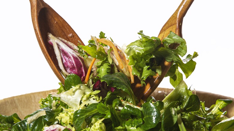 woman tossing salad in bowl