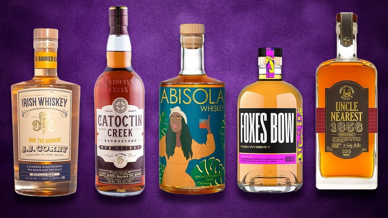 Five whiskey bottles on purple background