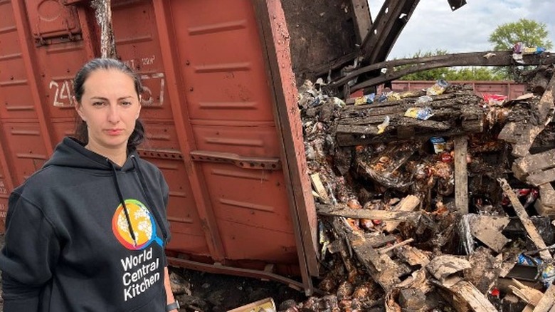 World Central Kitchen employee stands next to wreckage 