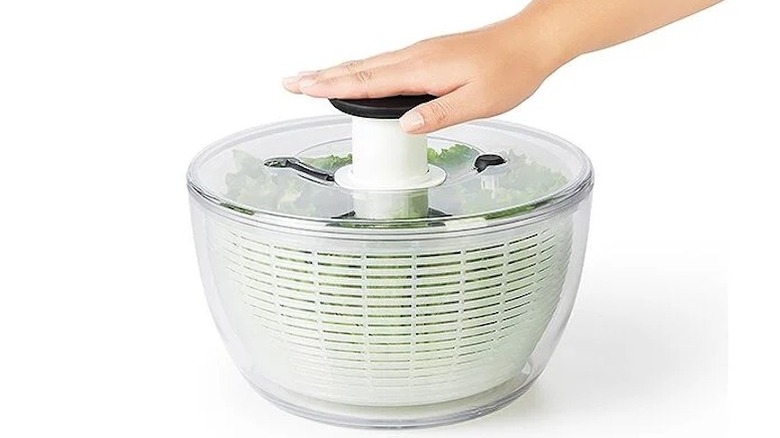 Hand pressing on OXO salad spinner