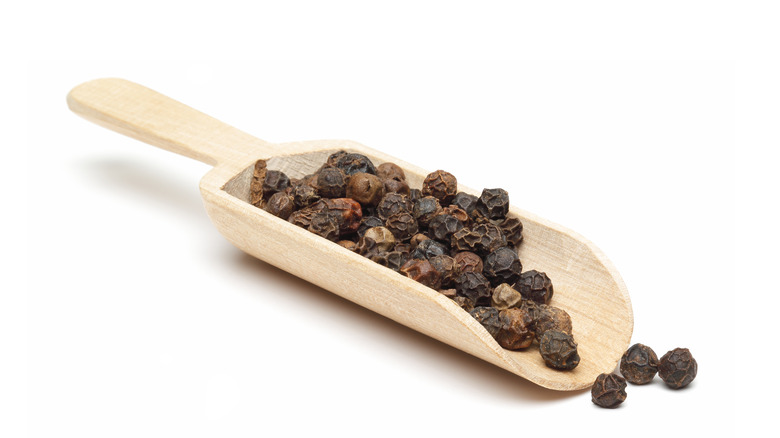 Wooden spoon with black peppers