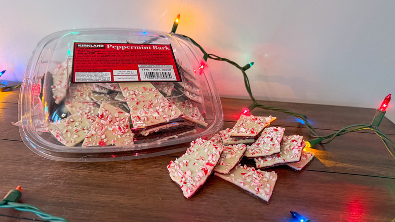 Package of Kirkland peppermint bark on a wooden table surrounded by Christmas lights