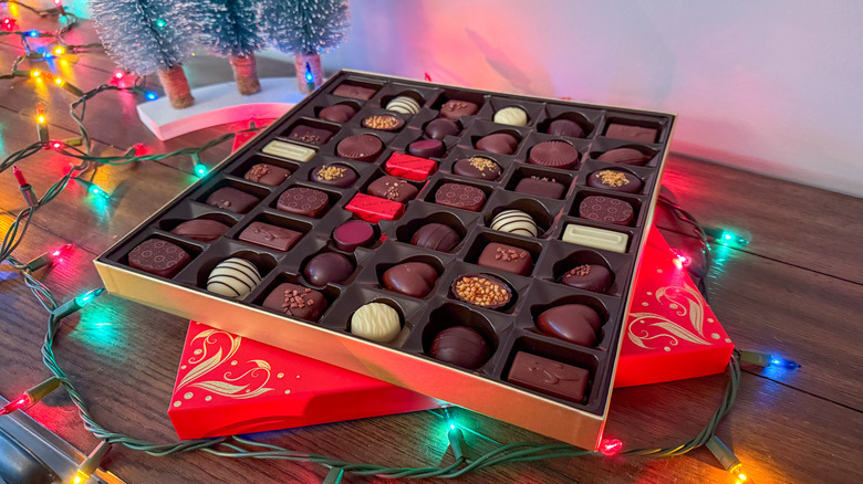 Box of Kirkland chocolates on a wooden table surrounded by Christmas lights