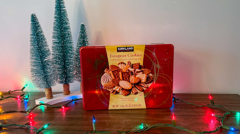 Red box of Kirkland cookies on a wooden table surrounded by decorations