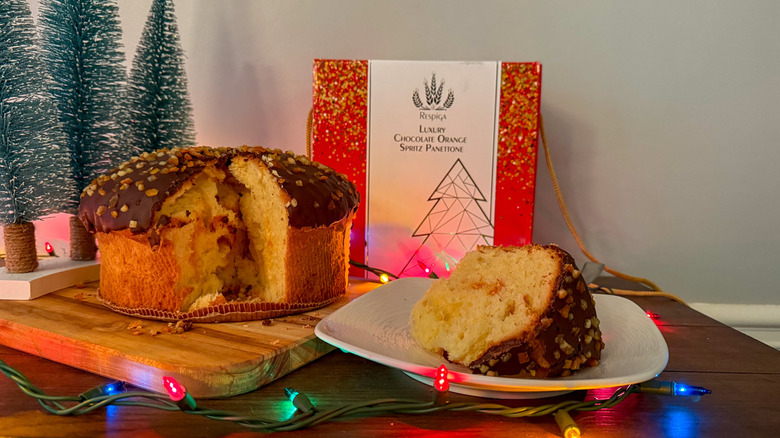 Slice of panettone on a white plate surrounded by box and decorations