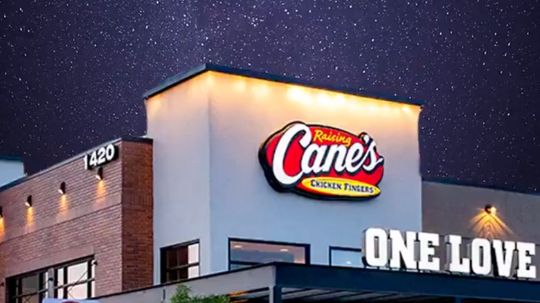 Raising Cane's restaurant sign from outside at night.