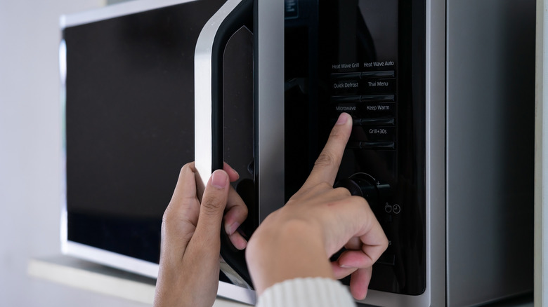 Hands programming a microwave