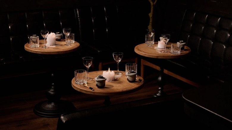 Small, empty tables with place settings in a dimly lit room at Sushi by Scratch