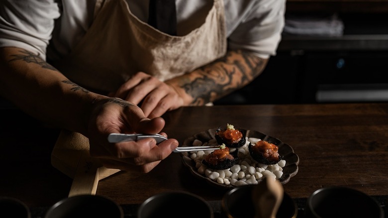 Chef using tweezers to place wasabi on an omakase dish