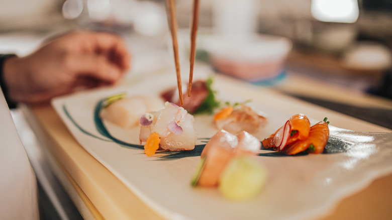 Person using chopsticks to pick up a piece of nigiri