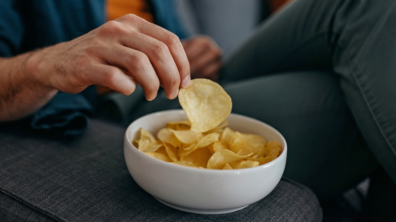 A hand grabs a potato chip