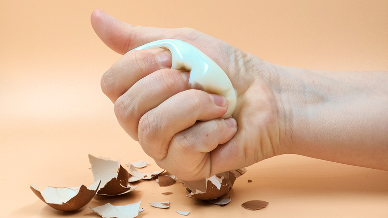 Hand crushing hard-boiled egg