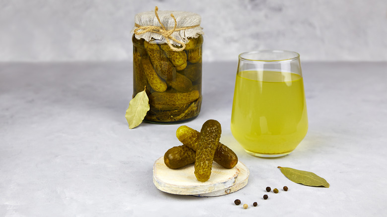 Pickles in a jar and pickle juice in a glass