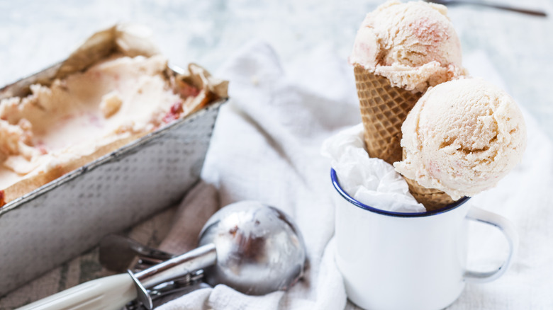 Container of ice cream next to cones