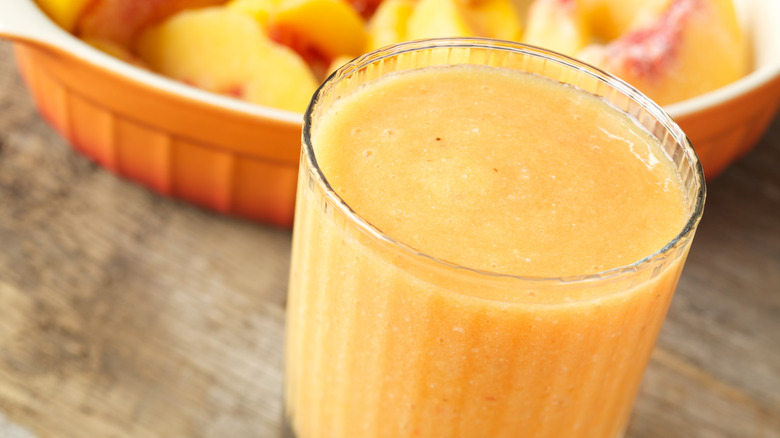 A glass of frozen peach and banana smoothie on wood table