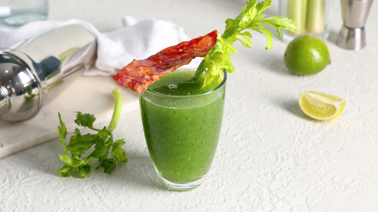 Green bloody mary cocktail garnished with bacon