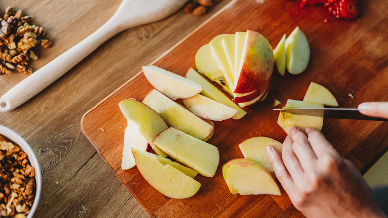 hands slicing apples on board