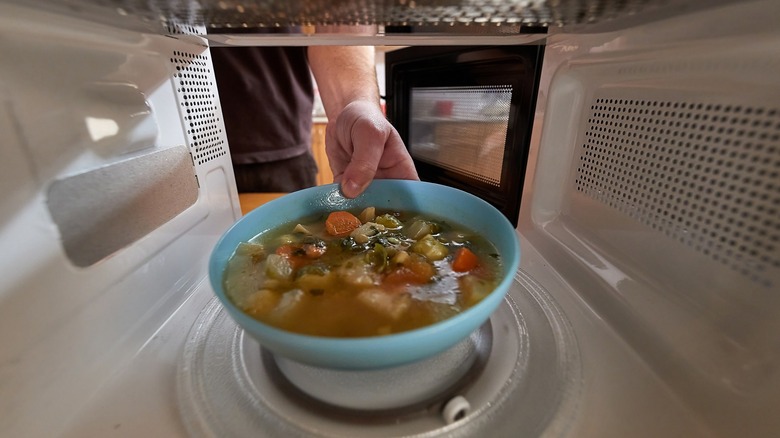Bowl of vegetable soup in microwave