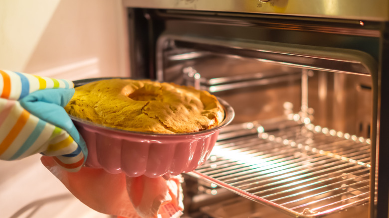 hands removing cake from oven