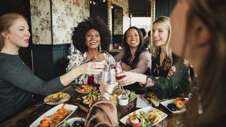 Group of women toasting with their elbows on the table