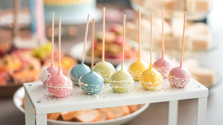 pastel colored cake pops on a white stand