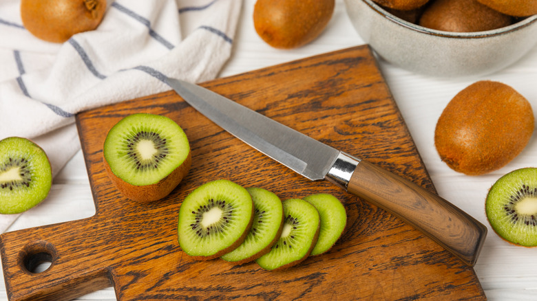 Sliced kiwi and a knife on a chopping board