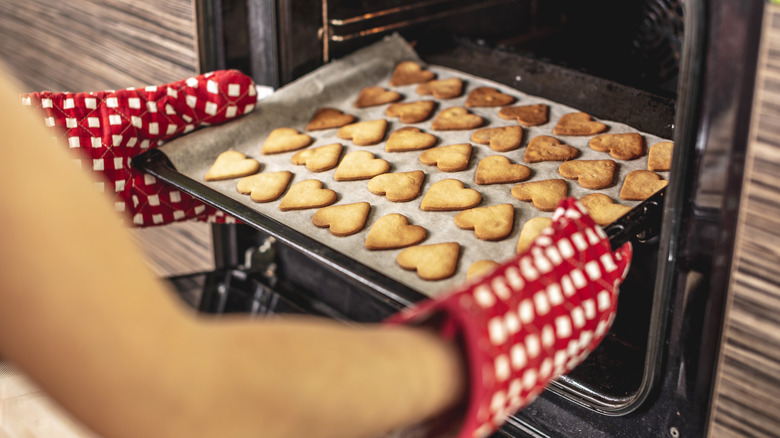 Heart-shaped cookies in a pan coming out of oven