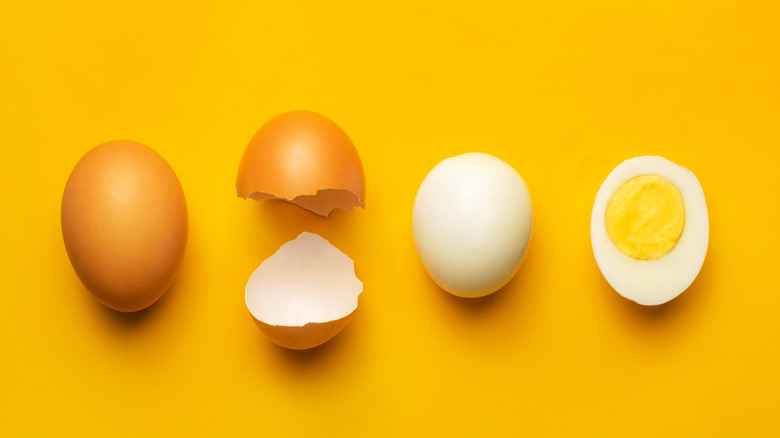 Egg with shell, cracked shell, a peeled boiled egg, and a halved boiled egg