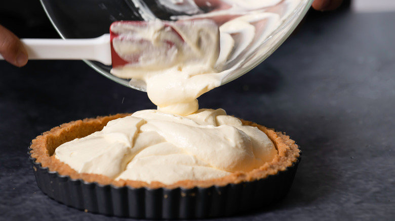 pouring cheesecake batter into pan