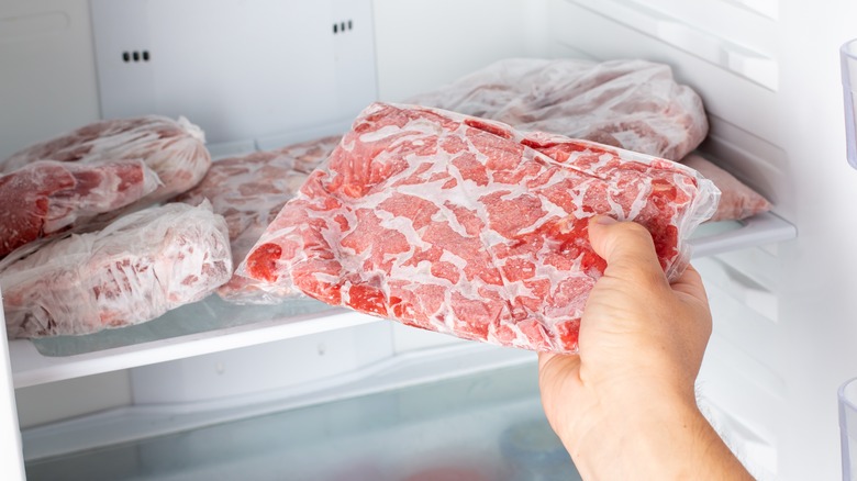 Hand pulls frozen meat from freezer